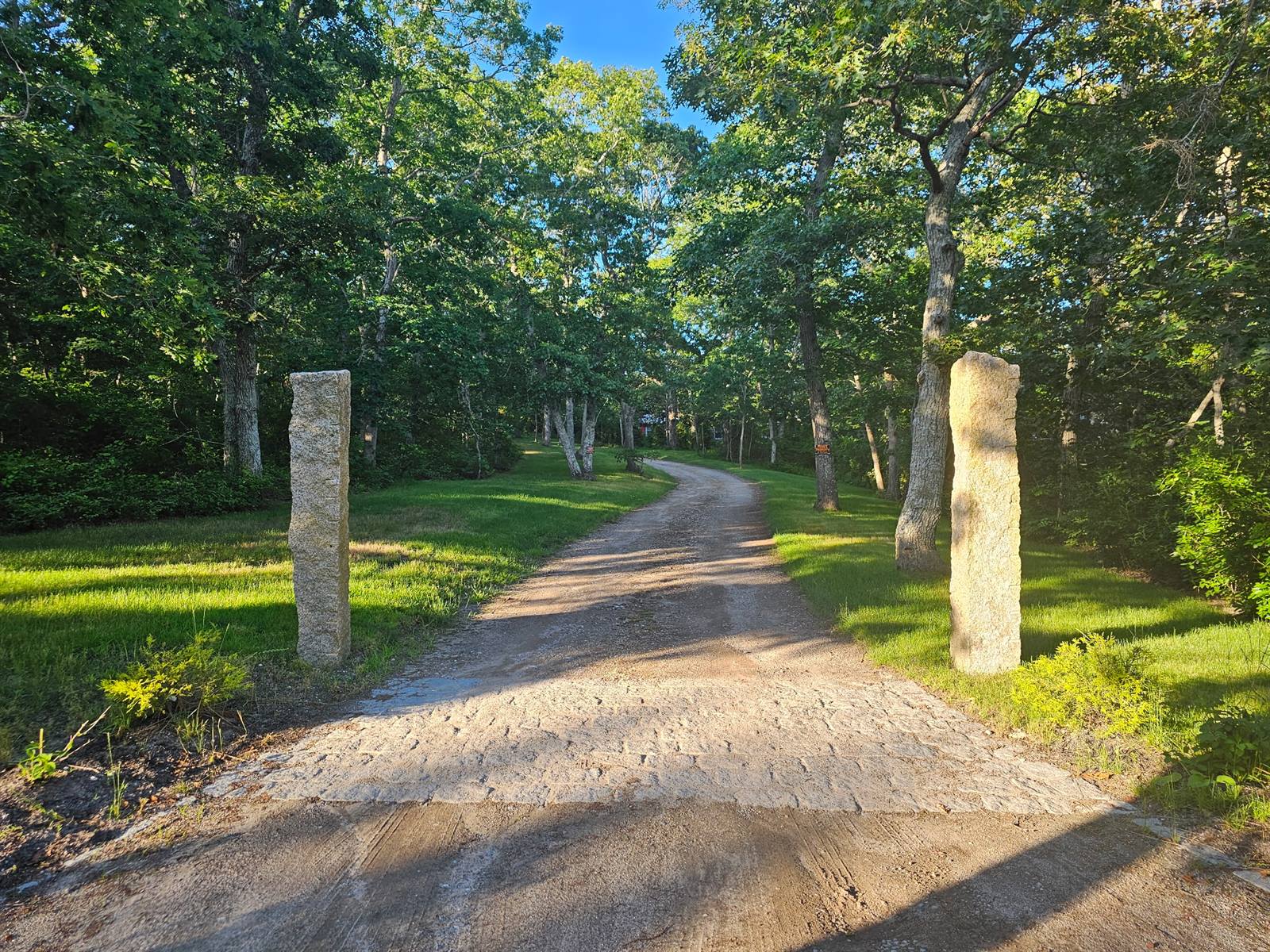 The granite pillars at the entrance to Osprey Point, the lane curving away through the oaks
